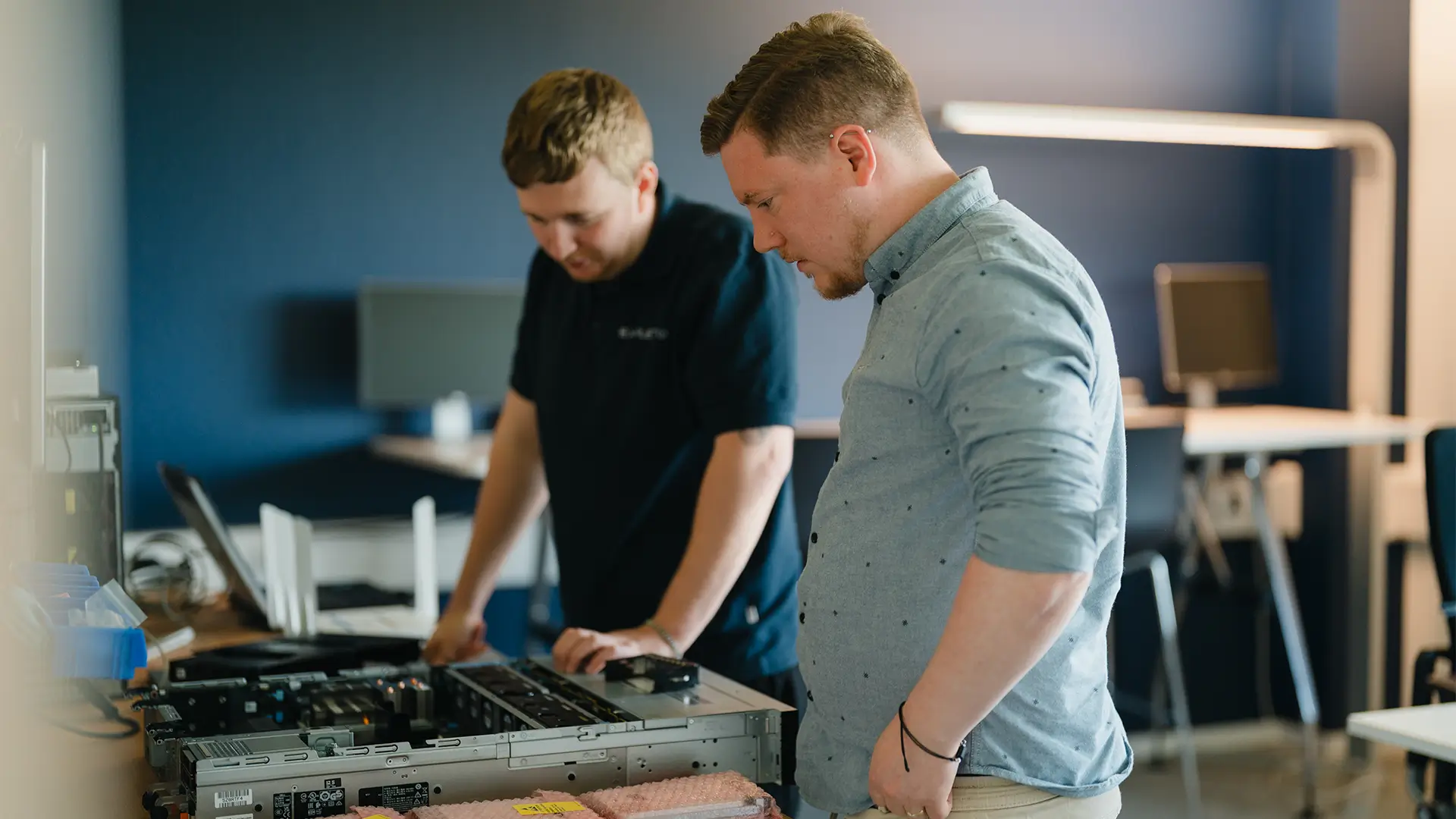 Zwei Mitarbeiter arbeiten gemeinsam an geöffneter Computer-Hardware in einer modernen Büroumgebung und prüfen technische Komponenten eines PCs.