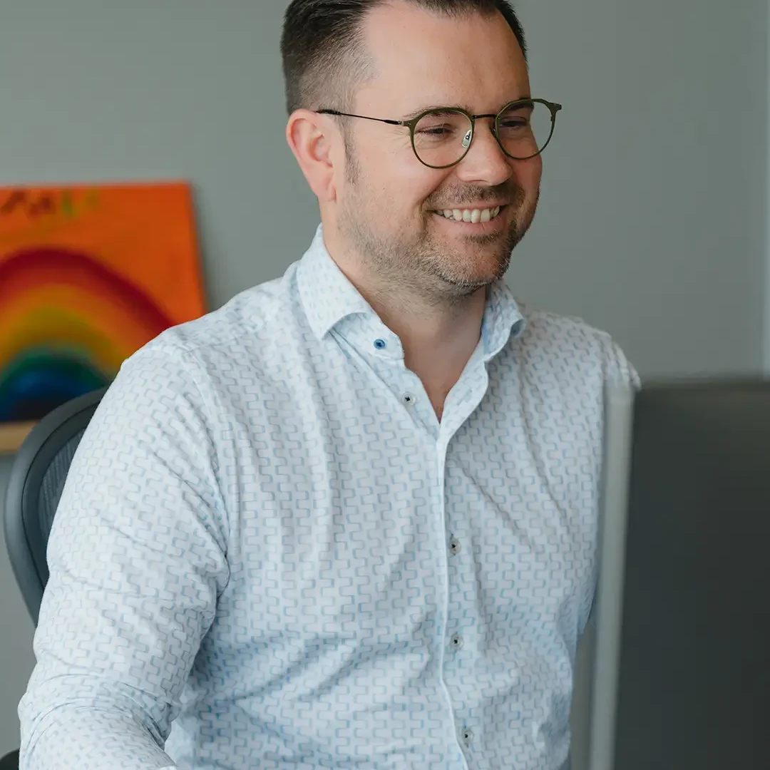 Geschäftsführer von EXPLETO lächelt bei der Arbeit am Computer an seinem modernen Büroarbeitsplatz.