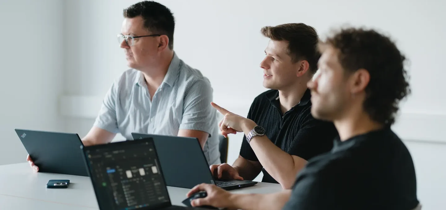 Drei EXPLETO-Mitarbeiter arbeiten gemeinsam an Laptops und tauschen sich während einer IT-Besprechung konzentriert über digitale Lösungen und Projekte aus.